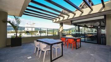 An outdoor terrace with a table and chairs, a potted plant, and a view of the cityscape.