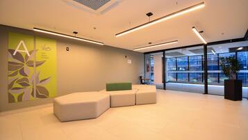 A modern reception area with a seating arrangement, a large window, and a wall with a floral design.
