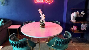 A dining area with a neon sign, a round table, and teal chairs. - Midtown Omahas, The Good Life Loft with view of downtown (Omaha)