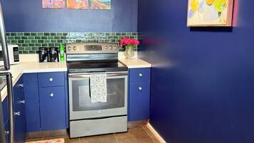 Una cocina con pared azul, estufa y microondas.