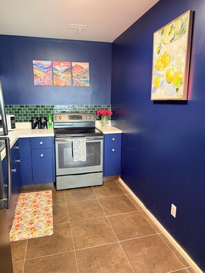 A kitchen with a blue wall, a stove, and a microwave.