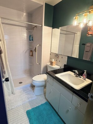 Un baño con ducha, inodoro, lavabo y toallero.
