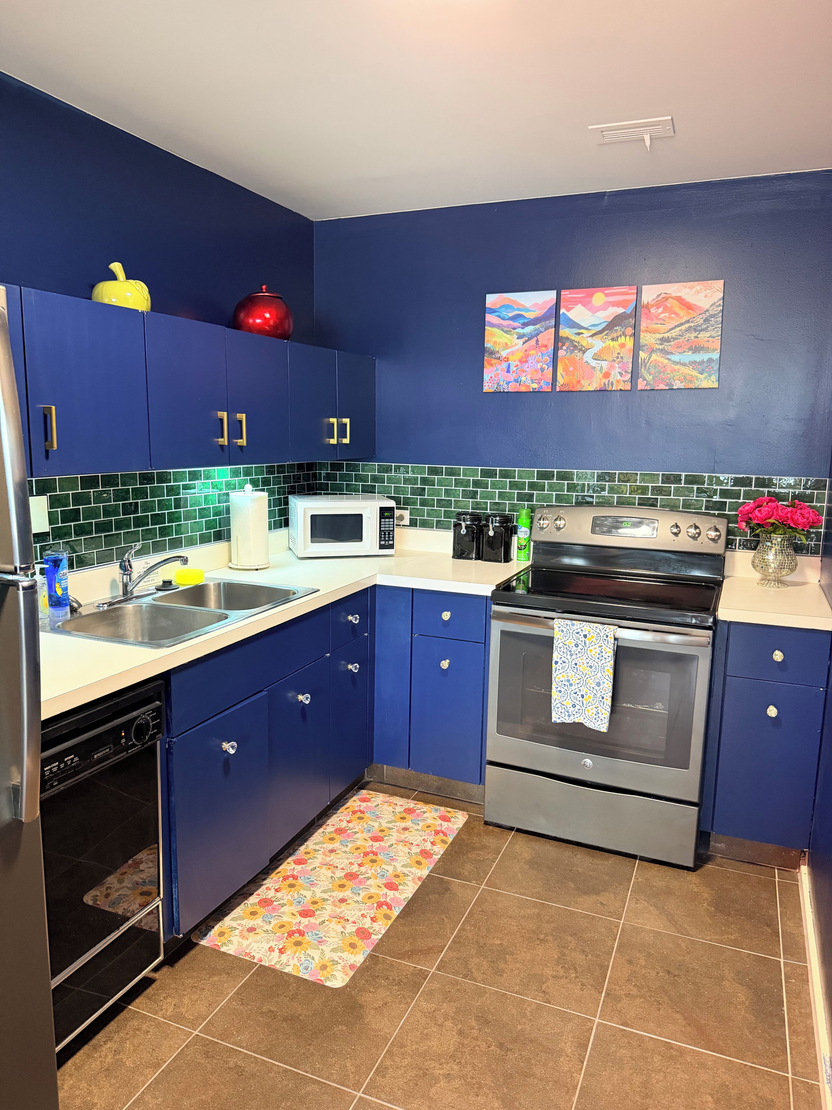 A kitchen with blue cabinets, a microwave, an oven, and a sink.