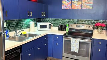 A kitchen with blue cabinets, a microwave, an oven, and a sink.