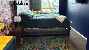 A bedroom with a bed, a nightstand, a TV, and a window with a view. - Midtown Omahas, The Good Life Loft with view of downtown (Omaha)