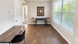 A room with a dining table, two chairs, a ceiling light, and a window with blinds. - Sleepover | Relaxing 1BD/1BA+ Gym - Corpus Christi (Corpus Christi)