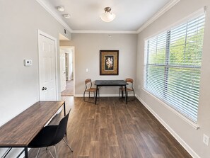 A room with a dining table, two chairs, a ceiling light, and a window with blinds. - Sleepover | Relaxing 1BD/1BA+ Gym - Corpus Christi (Corpus Christi)