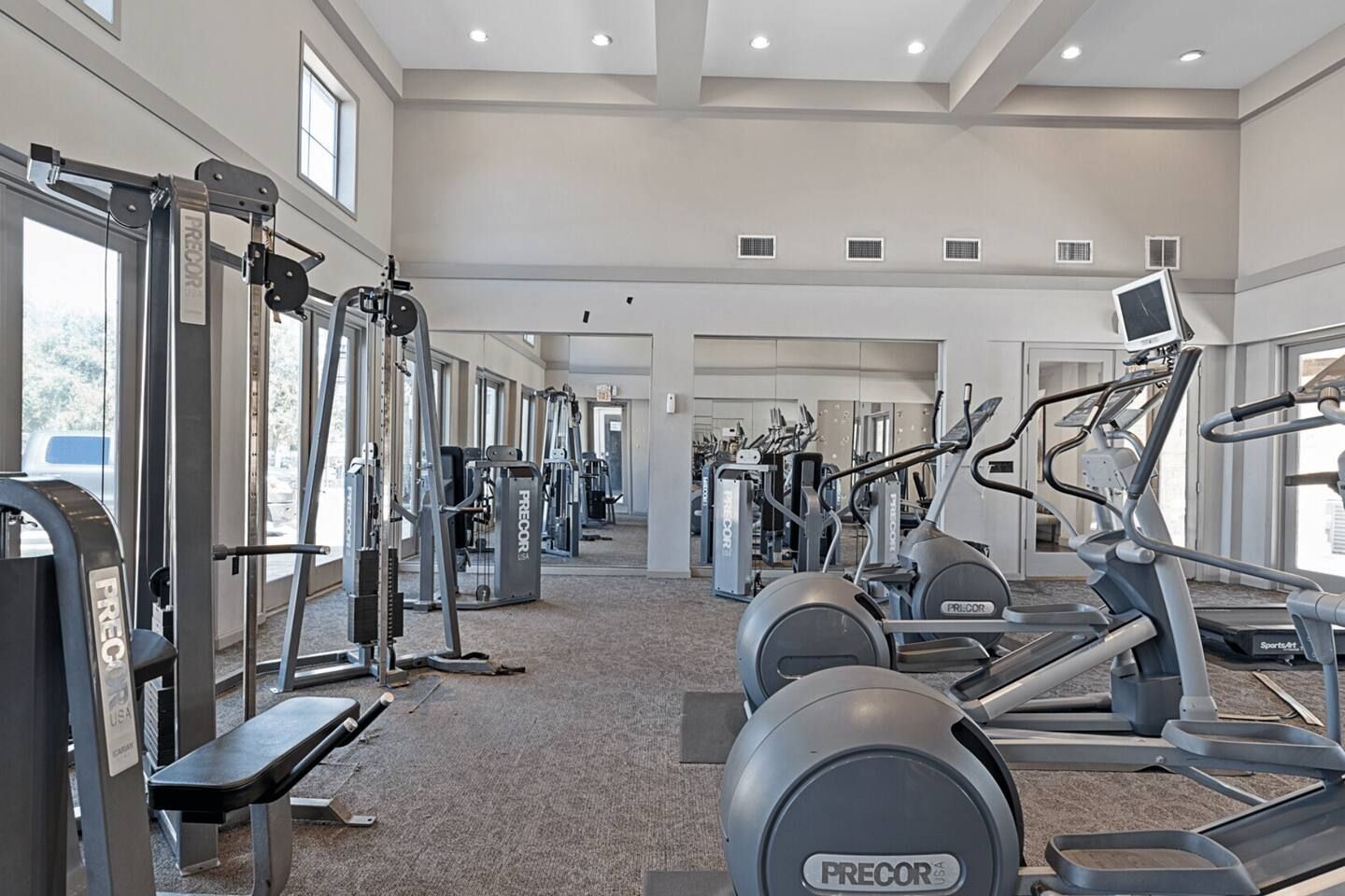 A gym with various exercise equipment including treadmills, elliptical machines, and weight machines.