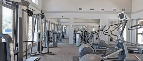 A gym with various exercise equipment including treadmills, elliptical machines, and weight machines.