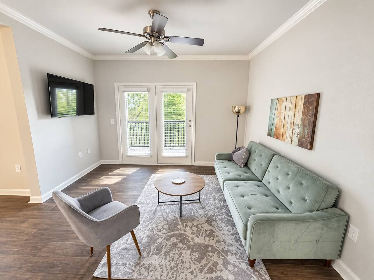 A living room with a sofa, armchair, coffee table, and a ceiling fan.