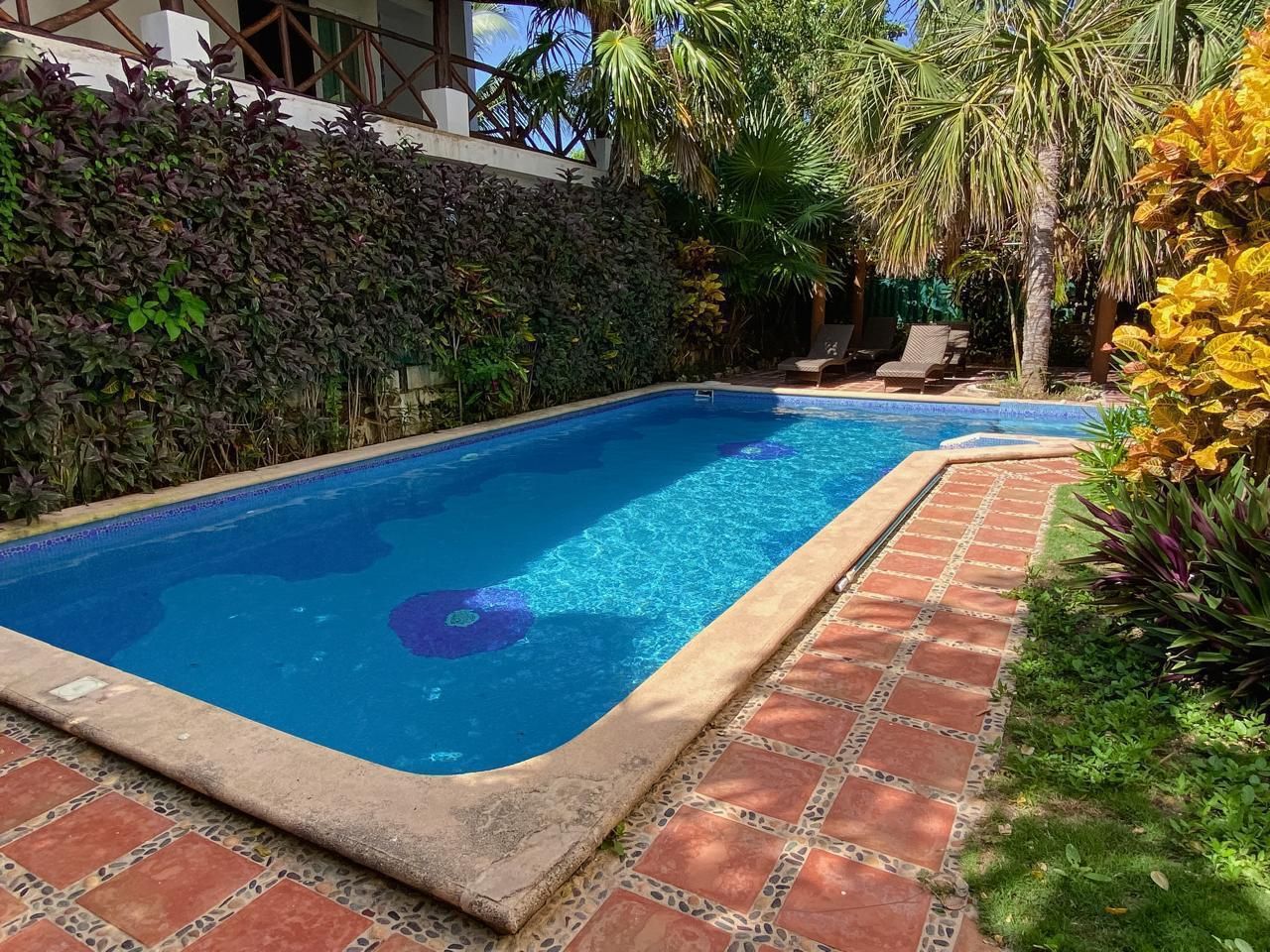 Una piscina rectangular amb aigua blava i transparent, envoltada d'un marc de maó i un passeig de rajola.