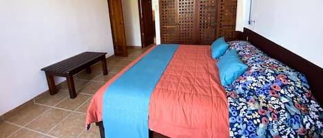 A bedroom with a bed, a ceiling fan, a bench, and a wooden partition.