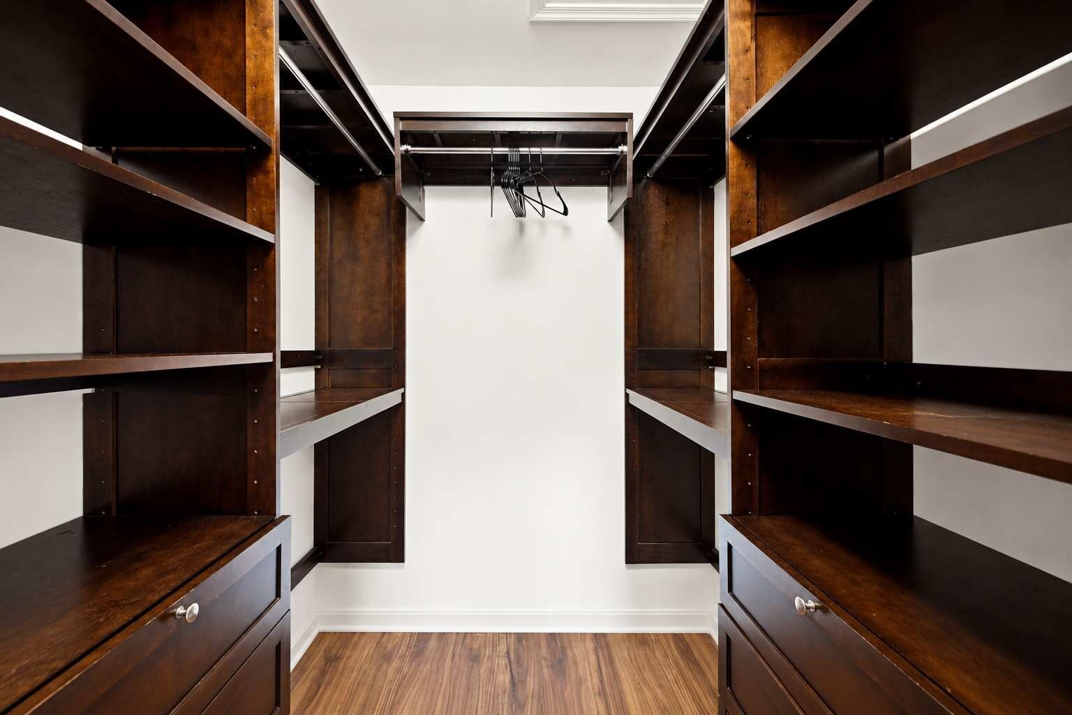 A walk-in closet with multiple wooden shelves and a white ceiling.