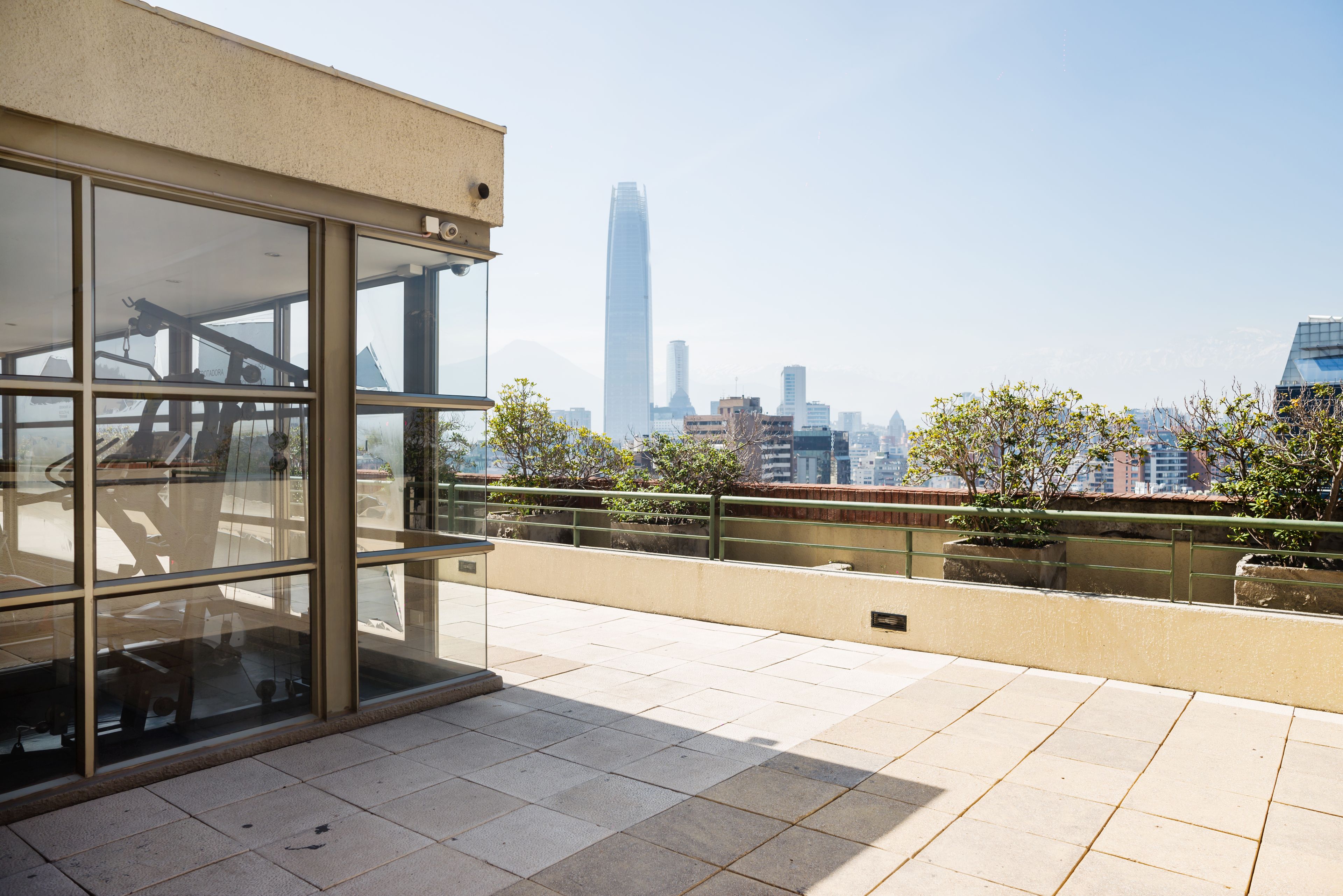 Ein modernes Gebäude mit großen Fenstern und einem Balkon mit Blick auf eine Skyline aus Hochhäusern.