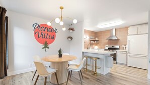 A modern kitchen with a central island, white cabinetry, and a dining area with a round table and chairs. - Perfectly located Home, Spa + Mini golf - Villa 2 (Ridgefield)