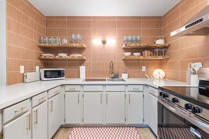 A modern kitchen with white cabinets, a microwave, a sink, and a stove.