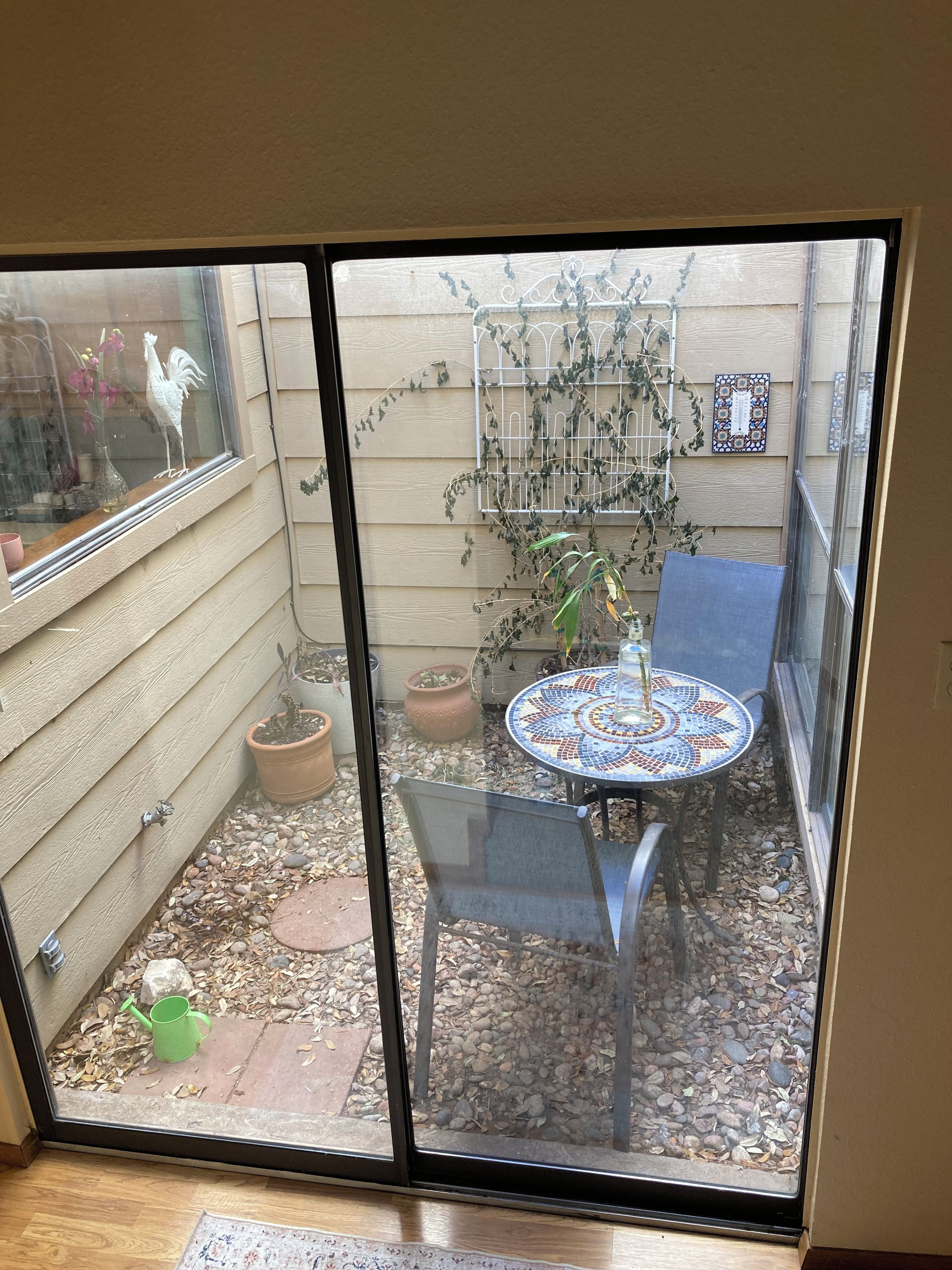 A patio with a table and chairs, a potted plant, and a decorative rooster.