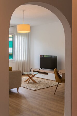 Een moderne woonkamer met een televisie, een glazen salontafel en een bank.