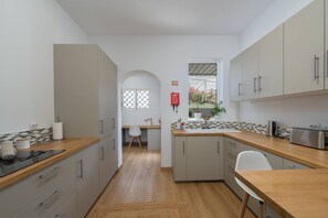 A compact kitchen with a wooden countertop, a sink, and cabinets. There is a window with a view of plants outside. - Casa dos Amigos by Galmi (Câmara de Lobos)