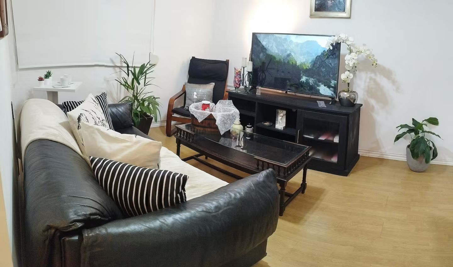 A living room with a leather sofa, a coffee table, a TV, and a bookshelf.