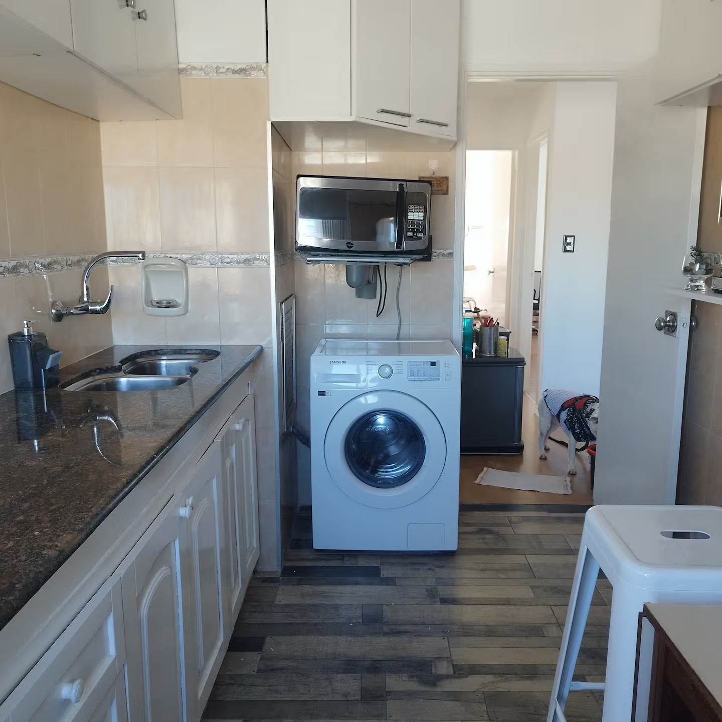 A compact kitchen with a built-in washer and dryer, a microwave, and a sink.