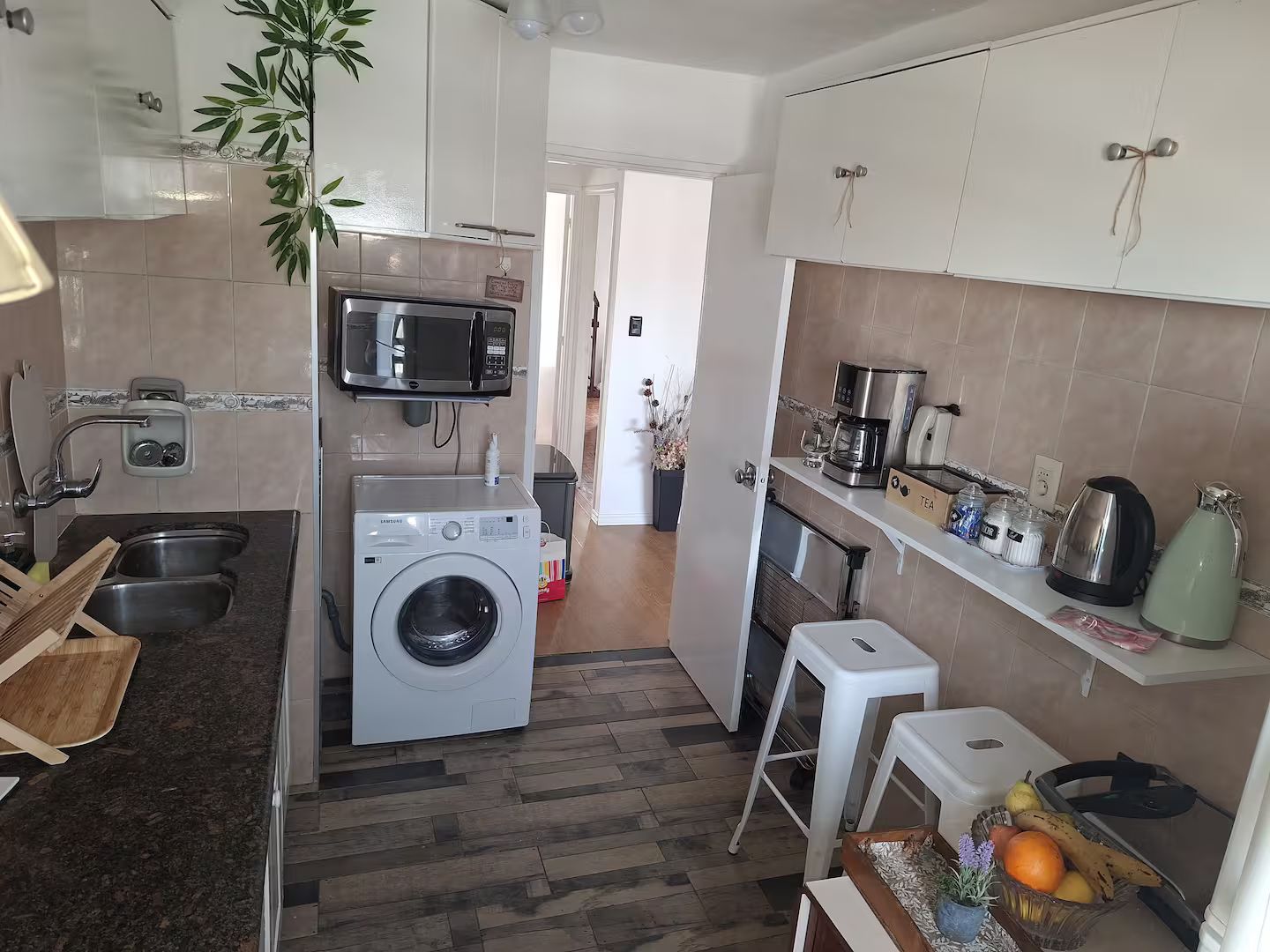 A compact kitchen with a washing machine, microwave, and a coffee maker.