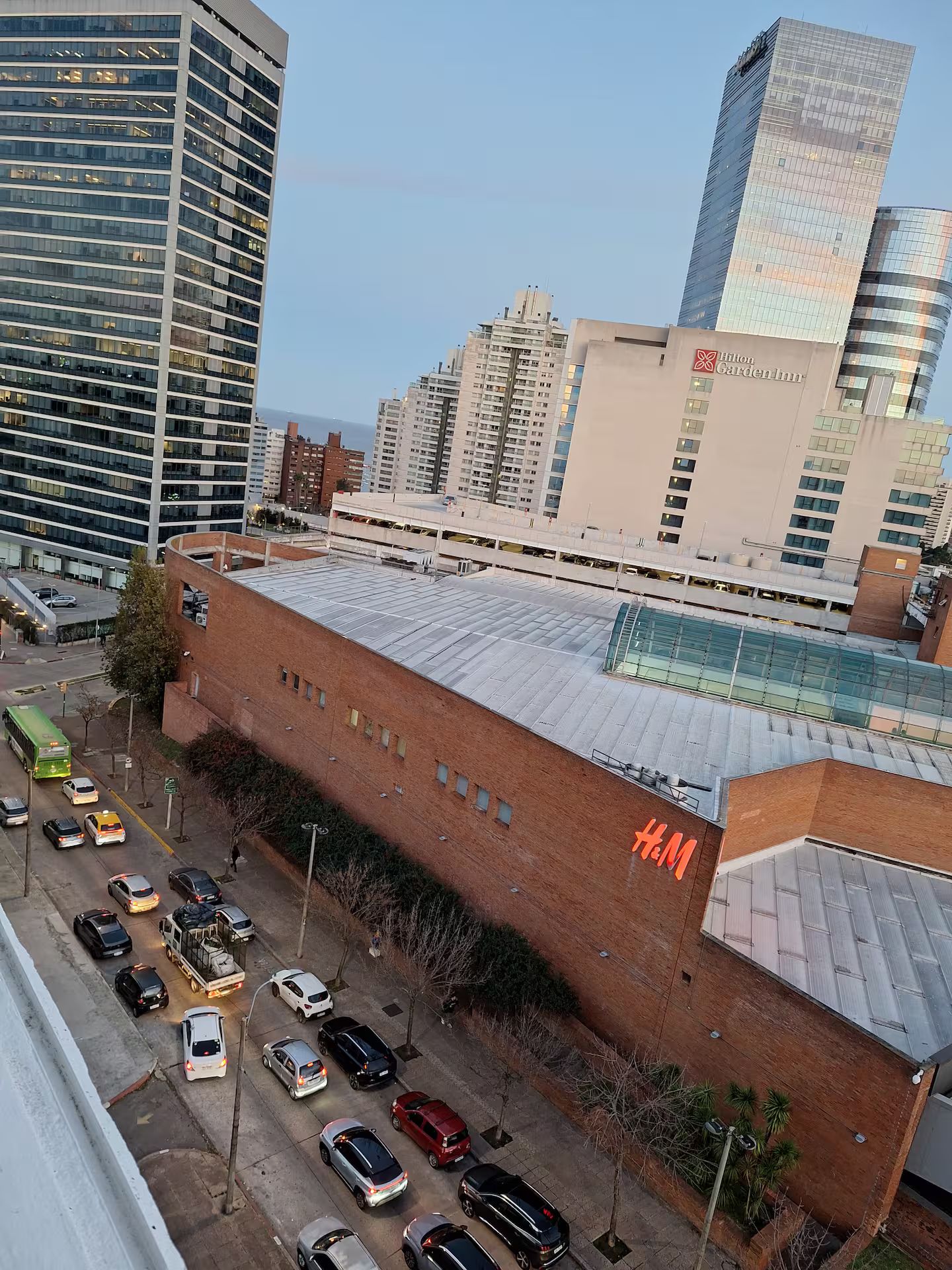 A multi-story building with a prominent H&M store on the ground floor, surrounded by other high-rise buildings.