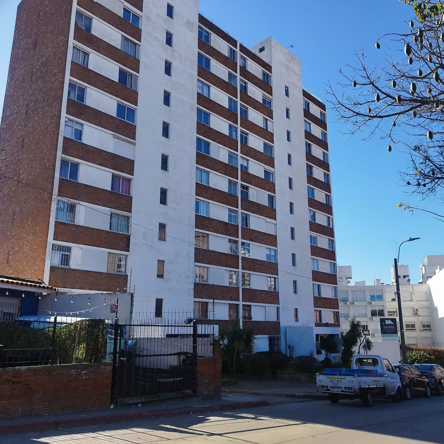 A multi-story residential building with a brick facade and white upper sections.