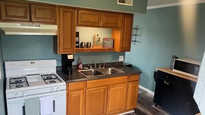 A kitchen with wooden cabinets, a white stove, a sink, and a microwave.