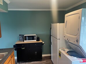 A compact kitchen with a microwave, refrigerator, and washing machine.