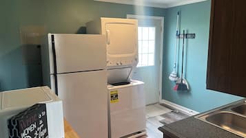 Una cocina compacta con refrigerador, horno y microondas. Hay un cartel en el refrigerador, una encimera de madera y una ventana con vistas.