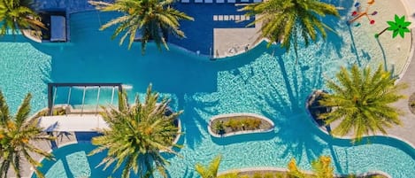 An aerial view of a pool area with palm trees, lounge chairs, and a clear blue pool.