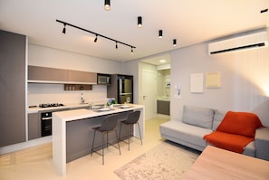 A modern apartment with a kitchen, dining area, and living room. - Studio Jardim Milano - CEN015 (Florianópolis)