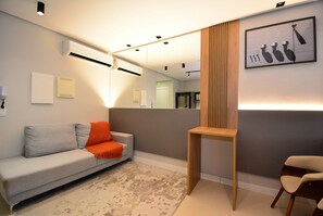 Ein modernes Wohnzimmer mit einem grauen Sofa, einem Holztisch und einem Teppich mit Muster.