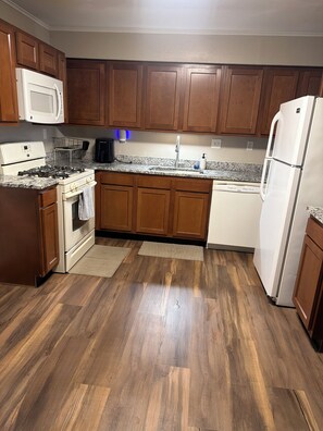A kitchen with wooden cabinets, a white refrigerator, a stove, and a microwave. - Cozy modern ranch retreat 2BR & 1BA (St. Louis)