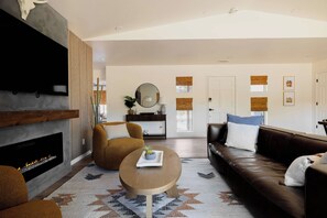 A modern living room with a fireplace, a sofa, a coffee table, and a television mounted on the wall. - Red Rock Views, Rooftop Patio, Hot Tub, Updated (Sedona)