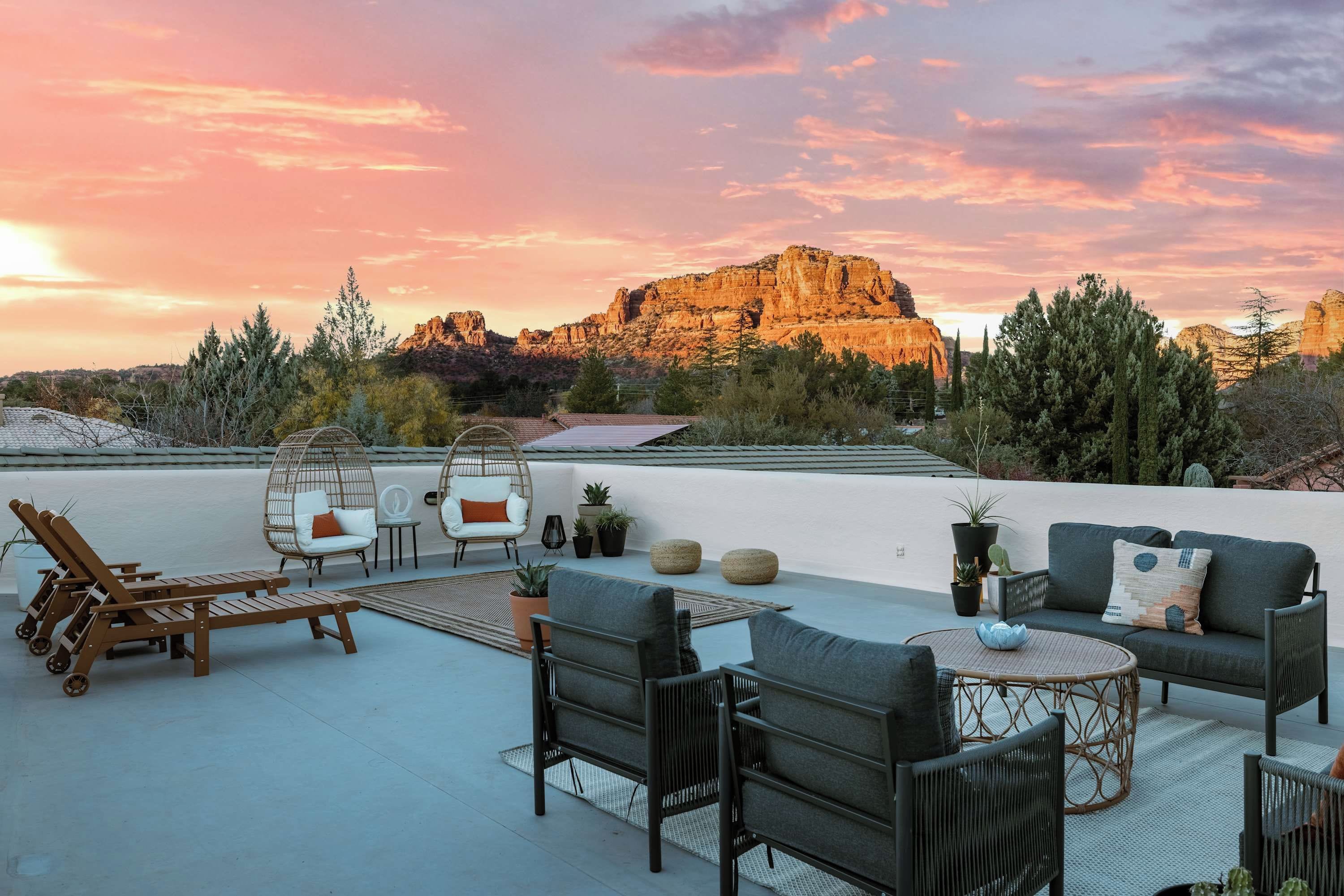 An outdoor seating area with a view of a mountain at sunset.
