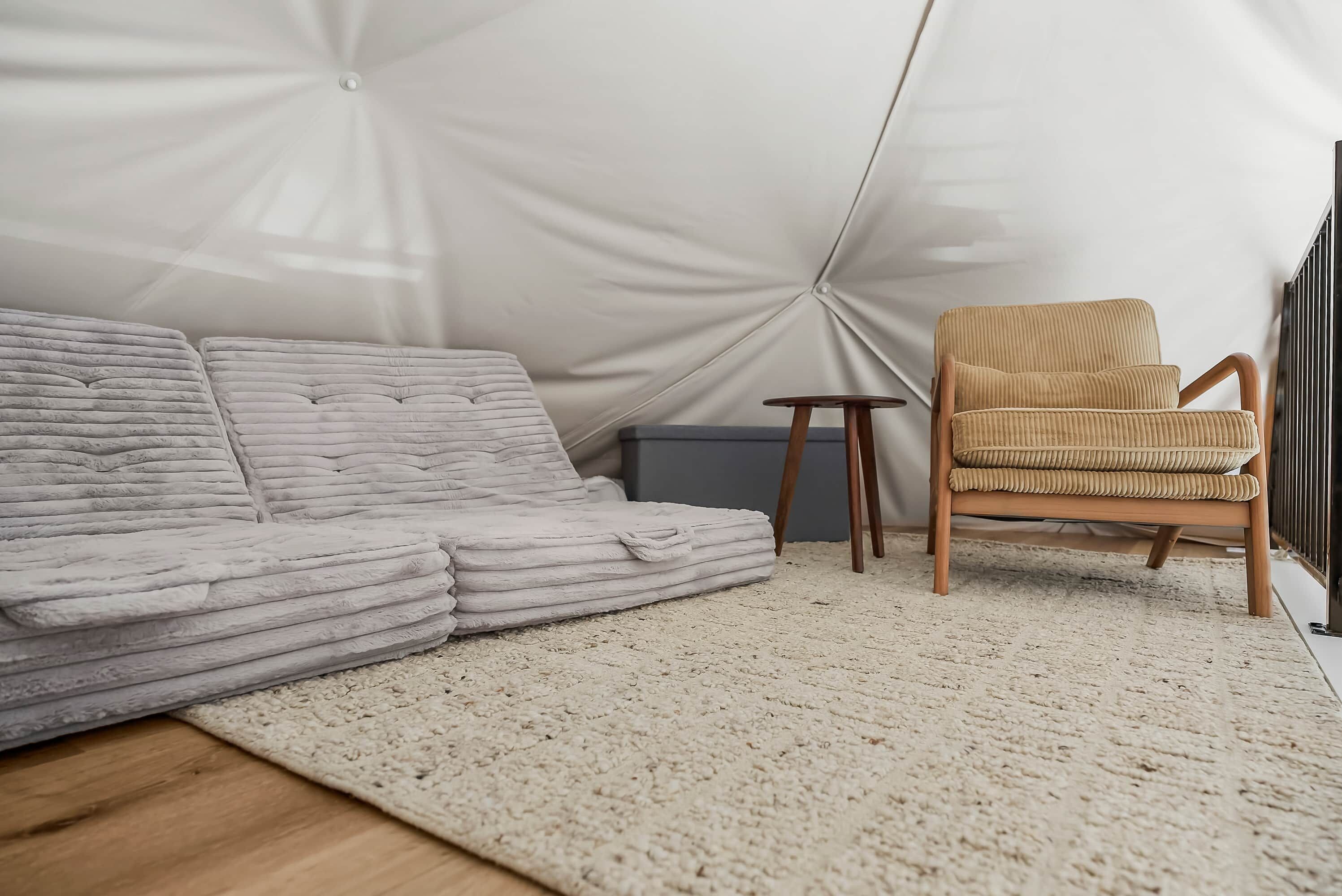 Une pièce comprenant un canapé, un fauteuil, une petite table et un radiateur.