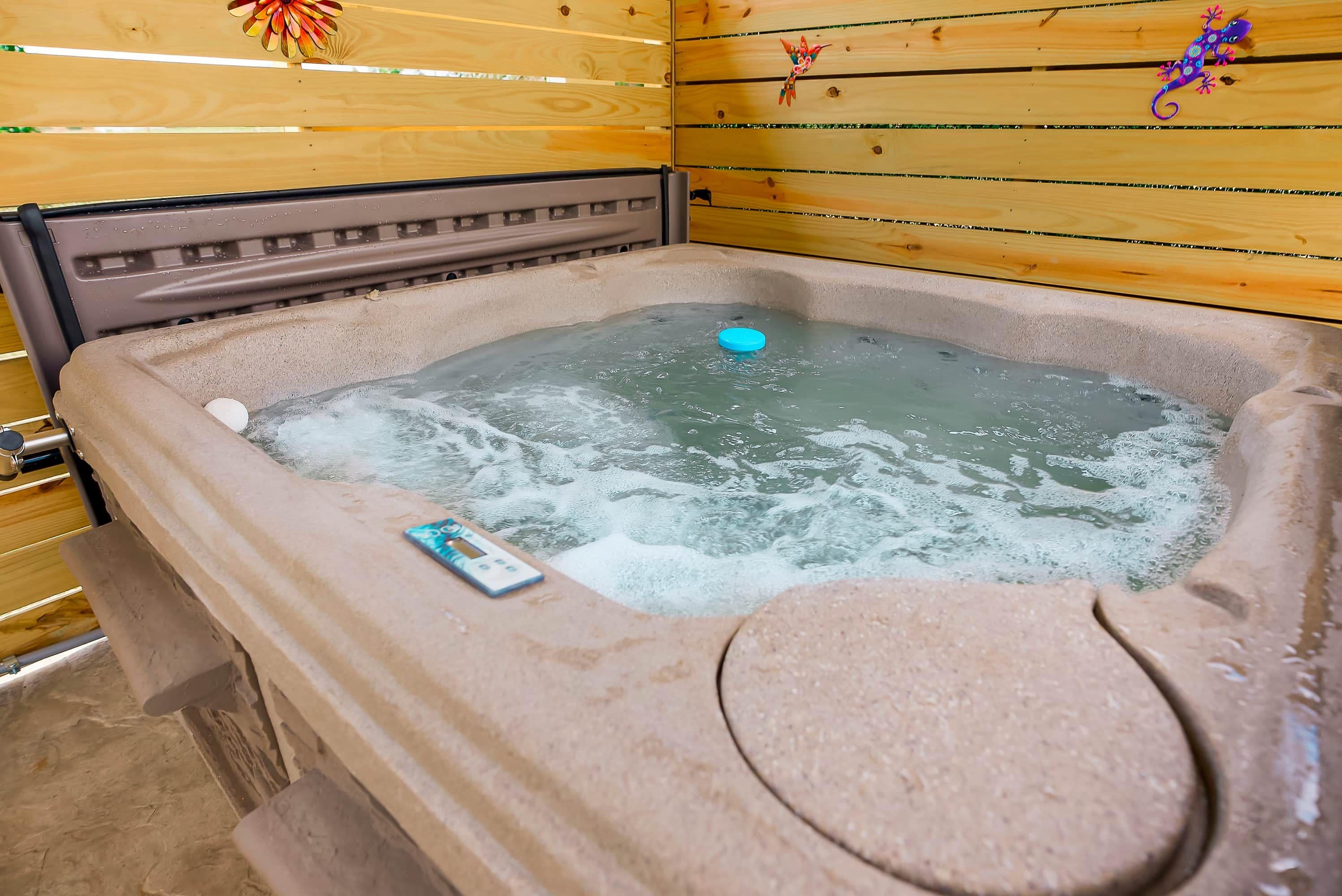 Un bain à remous doté d’un panneau de commande, entouré de murs en bois et surmonté d’un plancher en bois.