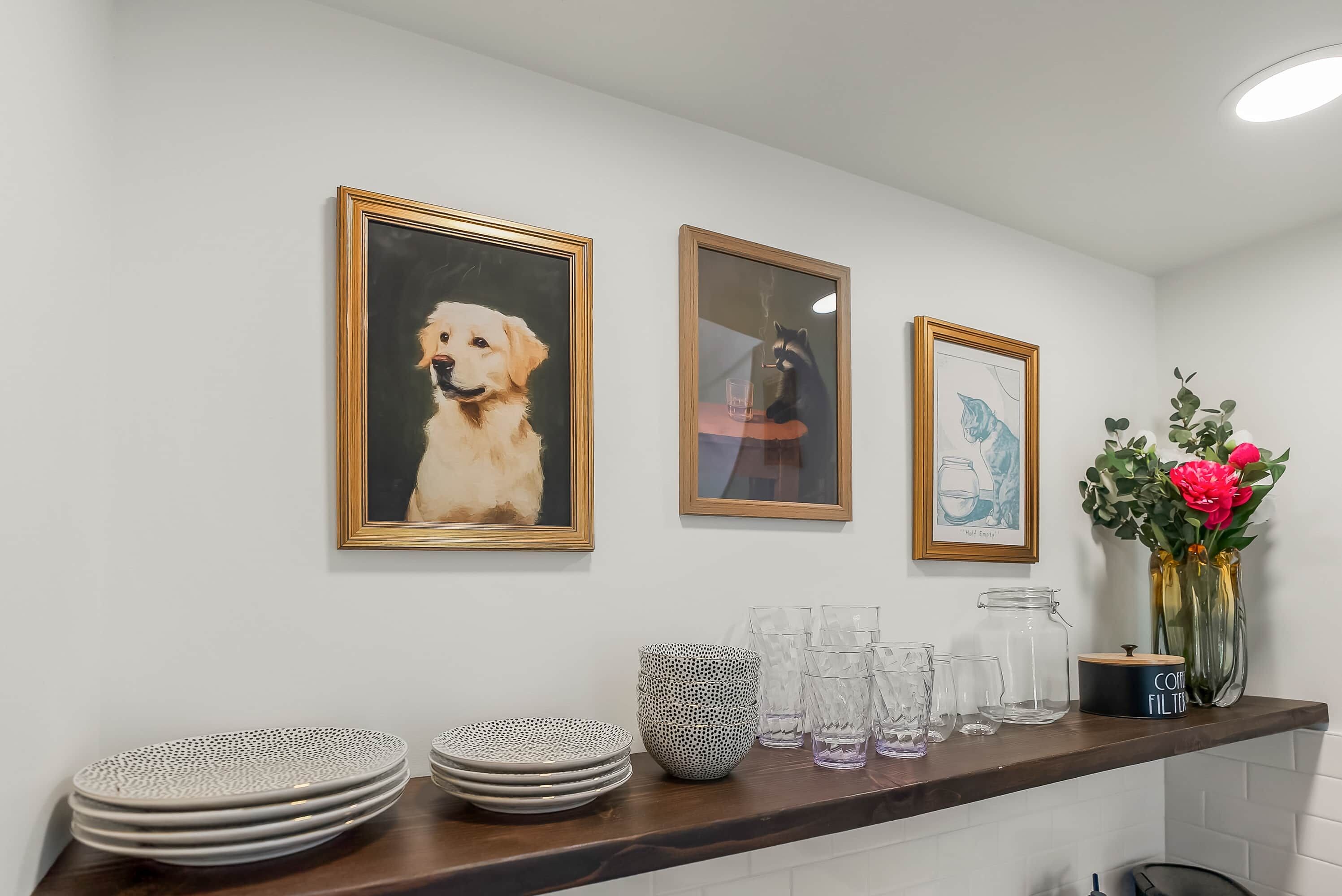 Una cucina con un piano di lavoro in legno, un vaso con fiori e quadri appesi al muro.