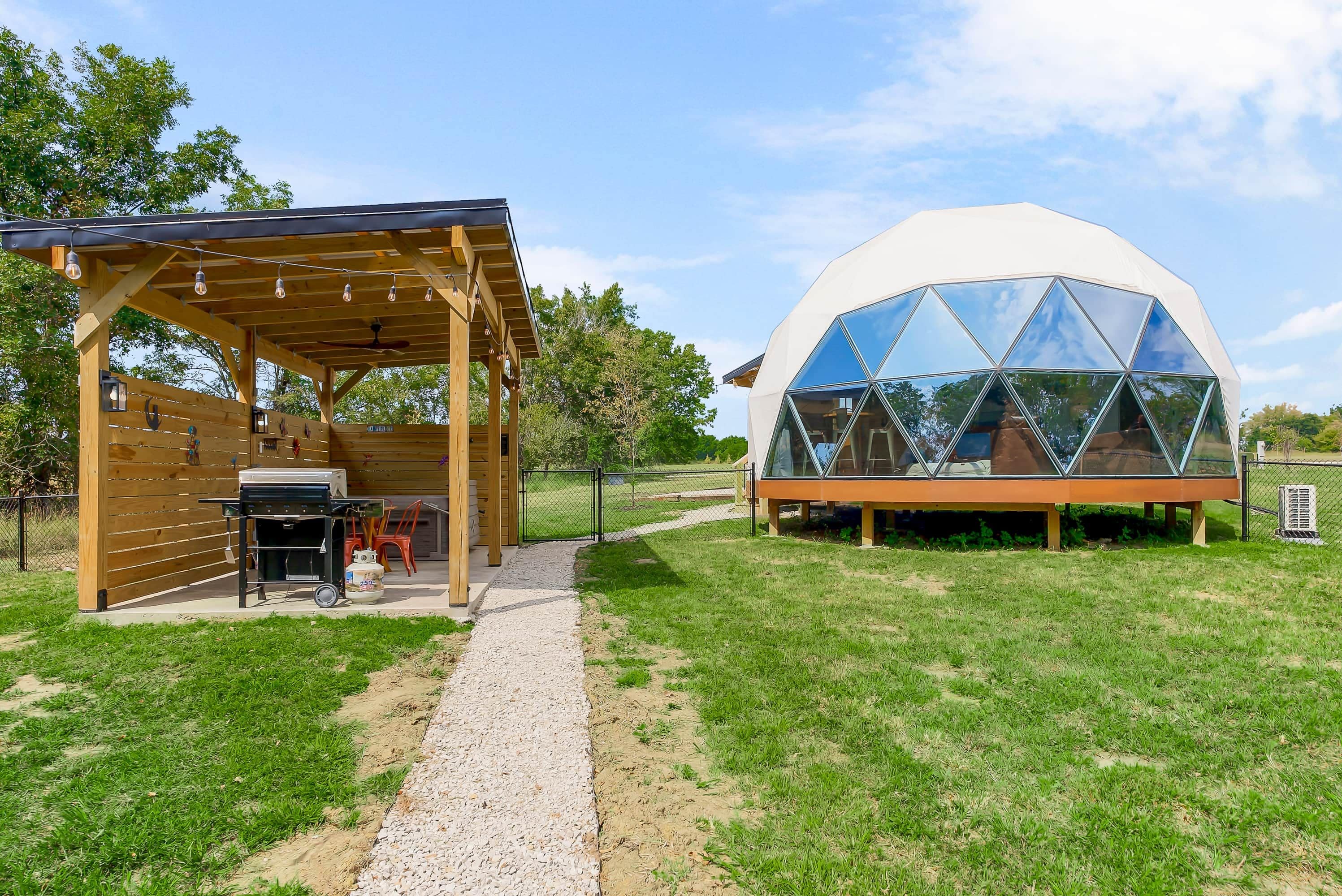 Eine Holzkonstruktion mit überdachter Terrasse und einer großen Geodätkuppel mit reflektierenden Glasscheiben.