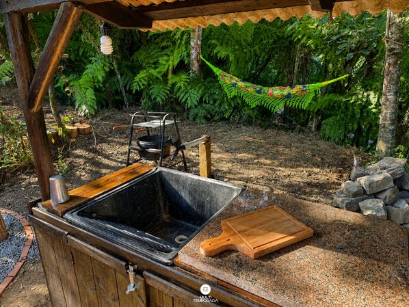An outdoor kitchen area with a sink, a cutting board, and a hanging hammock.