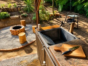 Un espacio al aire libre para cocinar con una parrilla, un fregadero y una tabla de cortar.