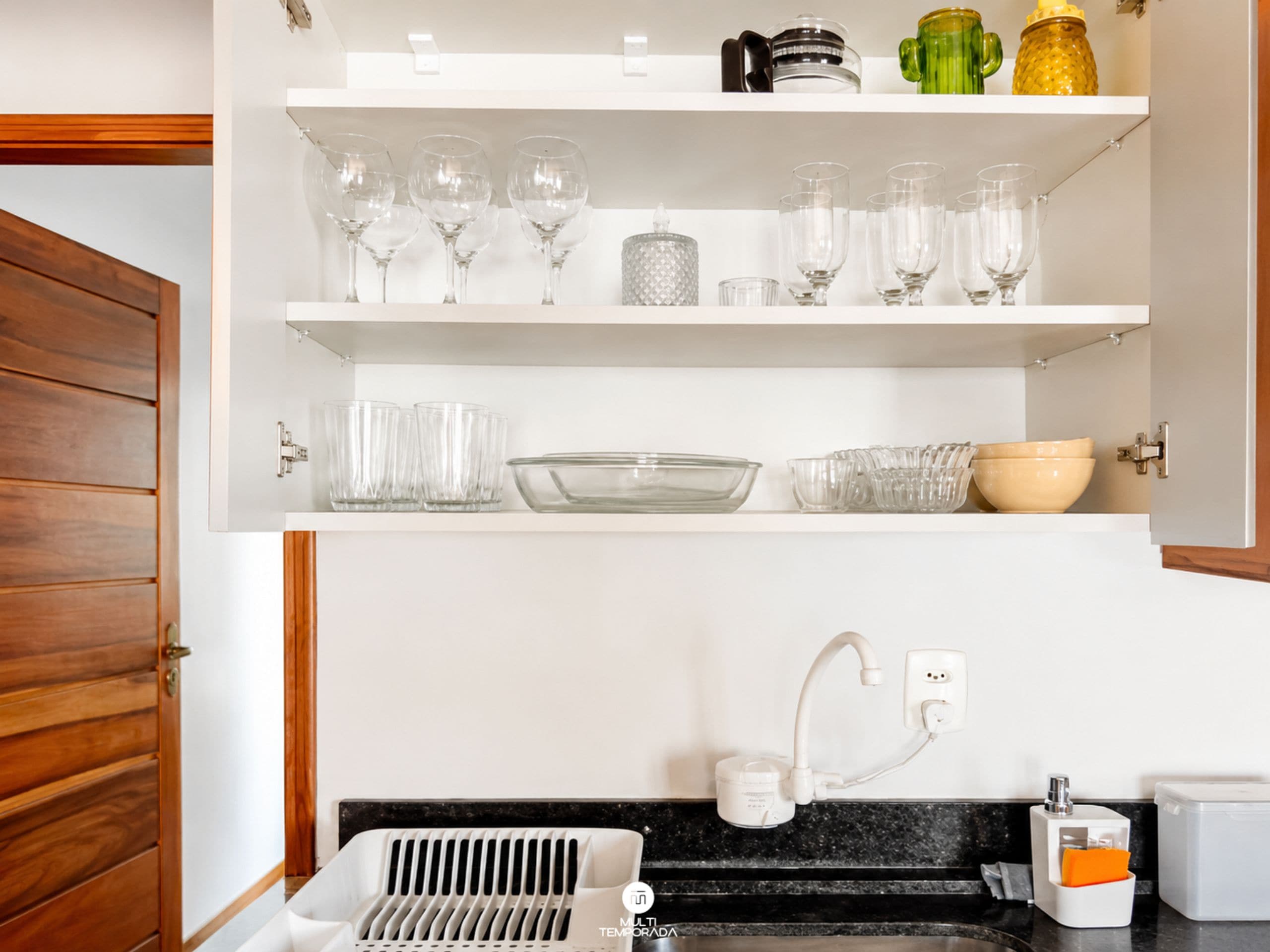 A kitchen with white cabinets, a black countertop, and a built-in dishwasher.
