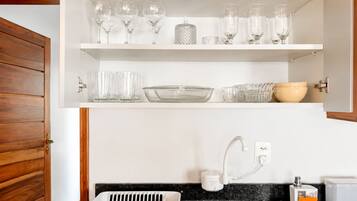 A kitchen with white cabinets, a black countertop, and a built-in dishwasher.