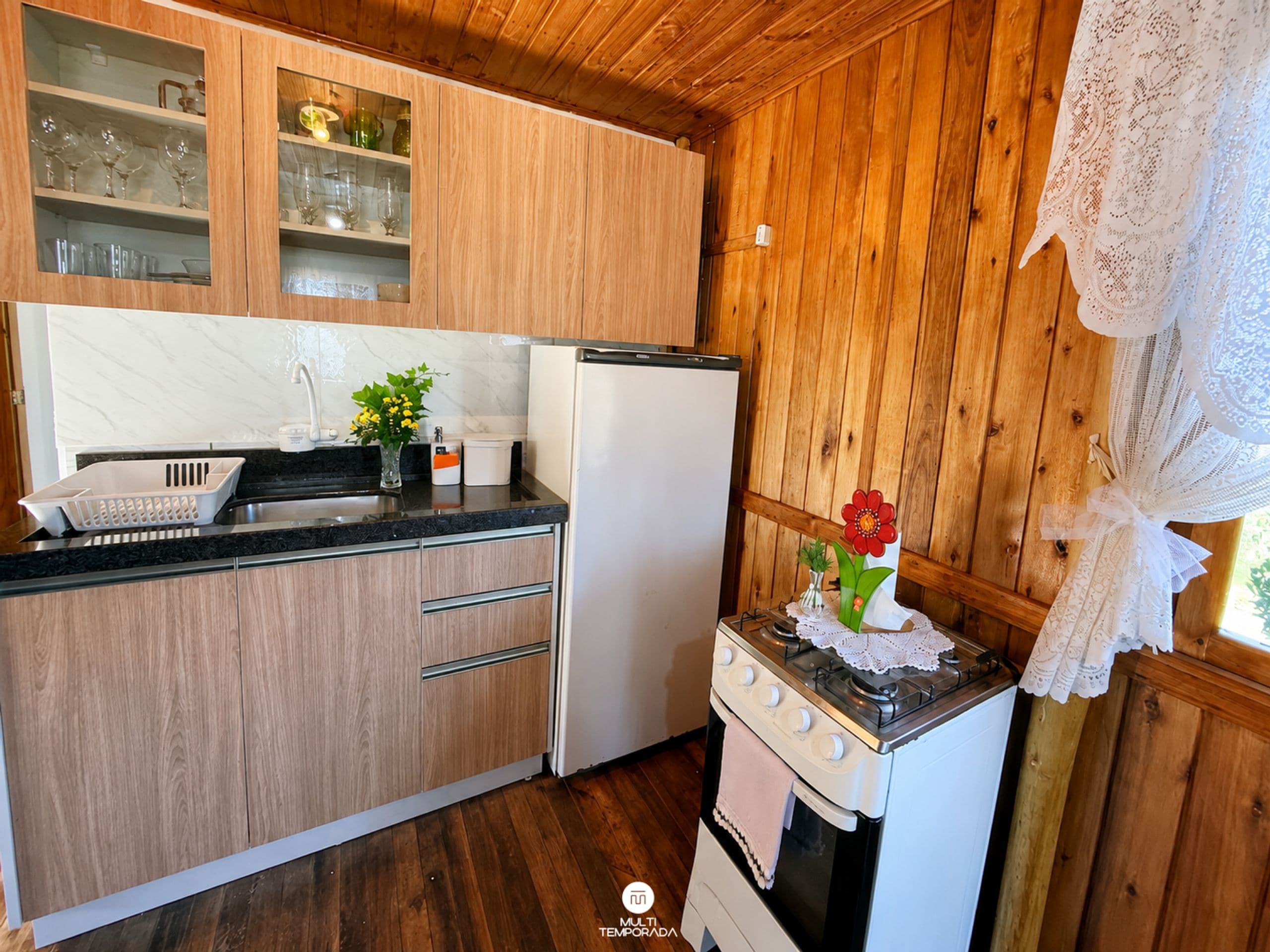 Una cocina con armarios de madera, un refrigerador, una estufa y un lavamanos.