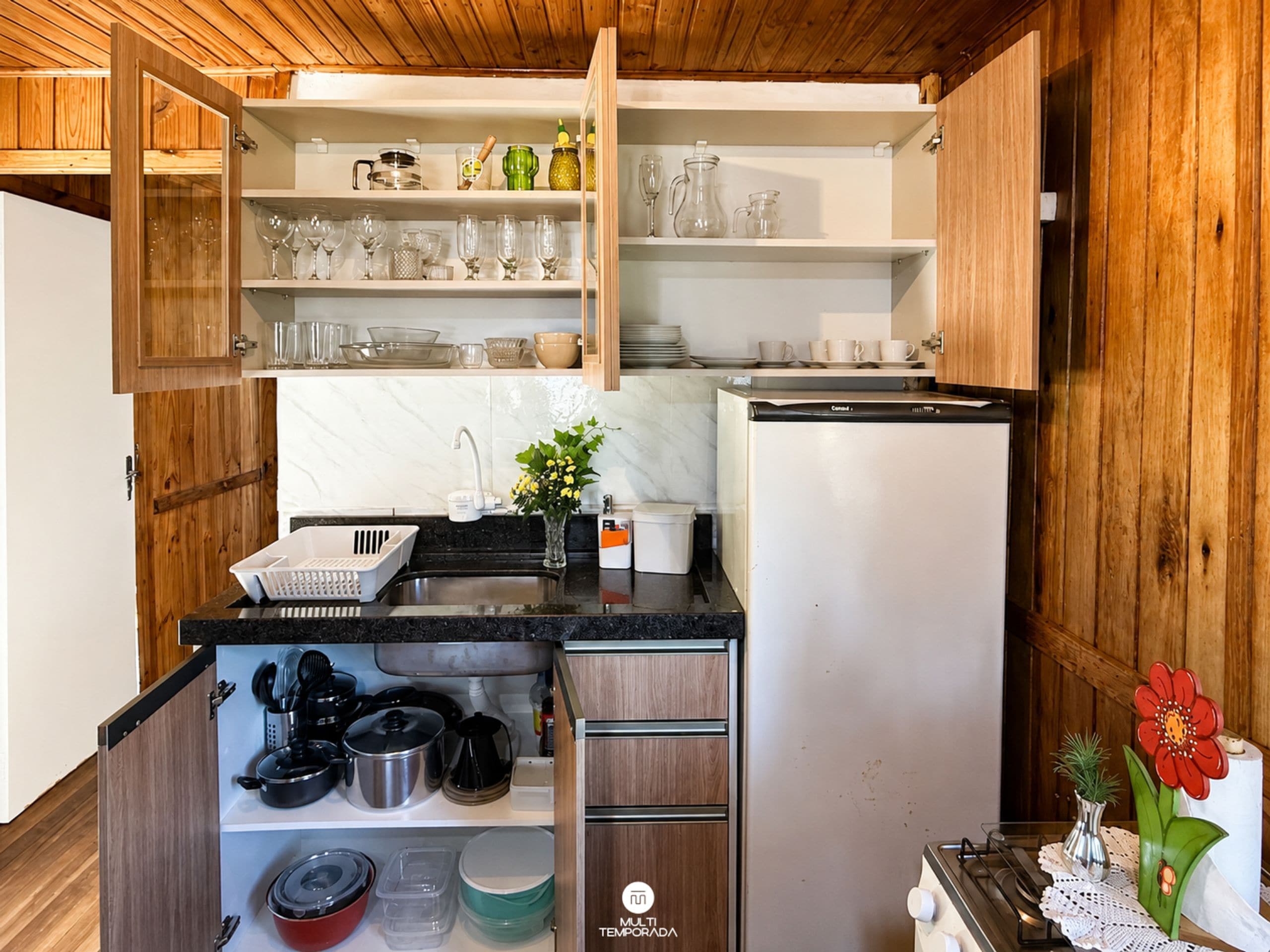 Een praktische keuken met houten kastjes, een inbouwvaatwasser en diverse keukengerei.