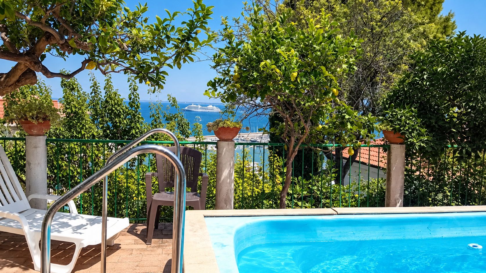 Ein Poolbereich mit Meerblick, ein Stuhl und ein Blumentopf.