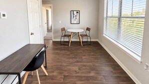 Una habitación con una mesa de comedor y sillas, una lámpara de techo, una ventana con persianas y una puerta.