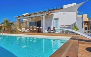 A modern poolside area with a clear blue pool, wooden deck, and lounge chairs. - Design villa with pool and jacuzzi near Selinunte (Triscina)